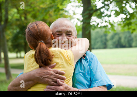 Donna che abbraccia un uomo anziano Foto Stock