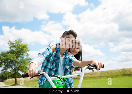 Un ragazzo e una ragazza equitazione sulla stessa bicicletta Foto Stock