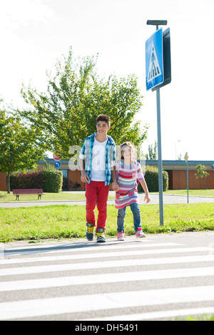 I bambini attraversando una zebra crossing Foto Stock