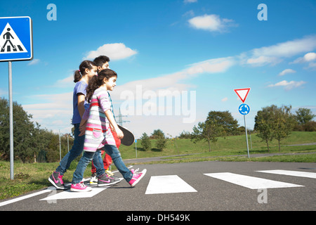 I bambini attraversando una zebra crossing Foto Stock