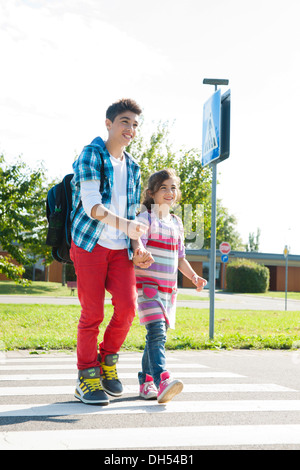 I bambini attraversando una zebra crossing Foto Stock