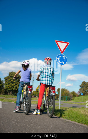 Bambini su biciclette a un semaforo con un corso di sensibilizzazione Foto Stock