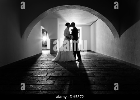 Sposa e lo sposo baciare sotto l'arco di un vecchio archivio, Rattenberg, Tirolo, Austria Foto Stock