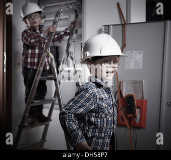 Due ragazzi che indossa caschi riproduzione di lavoratori edili, Kolsass, Unterland tirolese, Tirolo, Austria Foto Stock