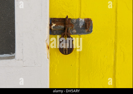 Rusty serratura e lucchetto su una luminosa gialla porta Foto Stock