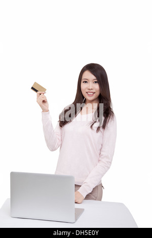 Giovane donna orientale in possesso di una carta di credito nella parte anteriore del computer Foto Stock