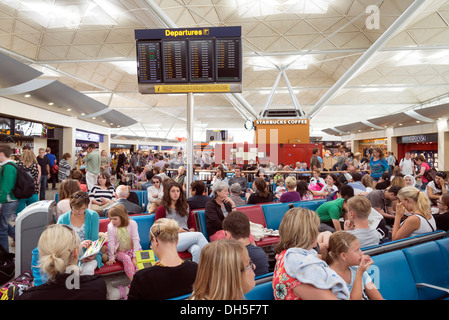 Persone in attesa nella affollatissima sala partenze dell'aeroporto di Stansted, England, Regno Unito Foto Stock