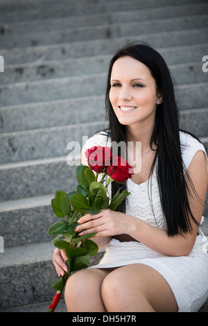 Giovane bella donna con rose rosse - outdoorf su scale Foto Stock