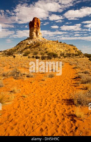 Stark outback australiano paesaggio - rosso immensa colonna rocciosa Camere pilastro infilzare nel cielo blu con ciuffi di nuvole bianche Foto Stock