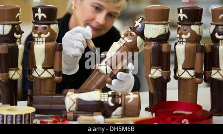 Hornow, Germania. 30 ott 2013. Dipendente Simone Bubner dal pasticcere Felicitas GmbH rimuove i bit del cioccolato da un cioccolato schiaccianoci in Hornow, Germania, 30 ottobre 2013. La produzione per il Natale ha già iniziato nell'impresa familiare. Solo il puro burro di cacao viene utilizzato per rendere le figure fatte a mano. Circa 300 chili di cioccolato è un processo lì ogni giorno. Foto: Patrick Pleul/dpa/Alamy Live News Foto Stock