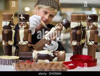 Hornow, Germania. 30 ott 2013. Dipendente Simone Bubner dal pasticcere Felicitas GmbH rimuove i bit del cioccolato da un cioccolato schiaccianoci in Hornow, Germania, 30 ottobre 2013. La produzione per il Natale ha già iniziato nell'impresa familiare. Solo il puro burro di cacao viene utilizzato per rendere le figure fatte a mano. Circa 300 chili di cioccolato è un processo lì ogni giorno. Foto: Patrick Pleul/dpa/Alamy Live News Foto Stock