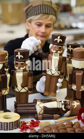 Hornow, Germania. 30 ott 2013. Dipendente Simone Bubner dal pasticcere Felicitas GmbH rimuove i bit del cioccolato da un cioccolato schiaccianoci in Hornow, Germania, 30 ottobre 2013. La produzione per il Natale ha già iniziato nell'impresa familiare. Solo il puro burro di cacao viene utilizzato per rendere le figure fatte a mano. Circa 300 chili di cioccolato è un processo lì ogni giorno. Foto: Patrick Pleul/dpa/Alamy Live News Foto Stock