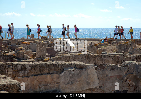 I turisti a piedi lungo la parete in corrispondenza di rovine di Nora in Sardegna meridionale Foto Stock