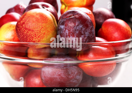 Le pesche noci e le prugne in una ciotola di vetro, close up Foto Stock