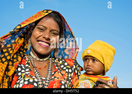 Sorridere le donne indiane con una sciarpa colorata tenendo un piccolo bambino in braccio, ritratto, Pushkar, Rajasthan, India Foto Stock