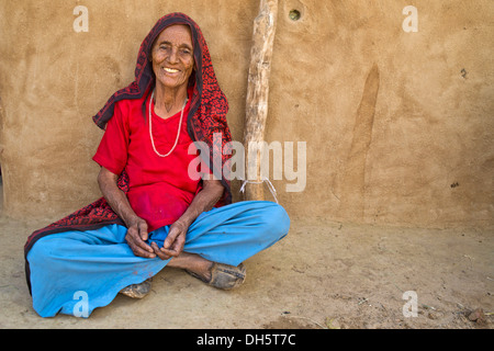 Il vecchio donna seduta sul terreno di fronte alla sua casa, Wüste Thar, Rajasthan, India Foto Stock