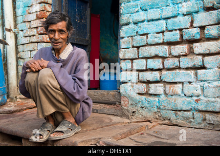 Anziani uomo seduto su un passo davanti a casa sua, Agra, Uttar Pradesh, India Foto Stock