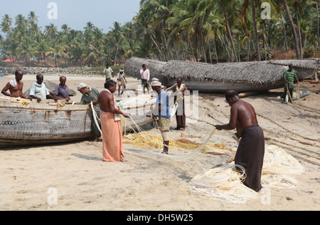 Gruppo di pescatori ordinamento le loro reti sulla spiaggia, Varkala Kerala, India, Asia Foto Stock
