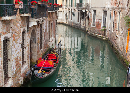 Venetian backstreet canal con gondola vuota Foto Stock