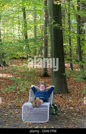 Donna relax nella foresta di autunno posa su una sedia Foto Stock