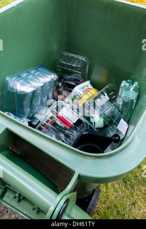 Green wheely cassone pieno di contenitori di plastica alimentare per il riciclaggio raccolta, REGNO UNITO Foto Stock