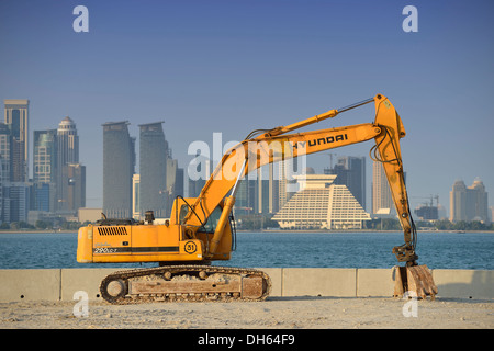 Boom edilizio a Doha, escavatore Hyundai di fronte allo skyline di Doha con Doha Sheraton Hotel Four Seasons Hotel Foto Stock
