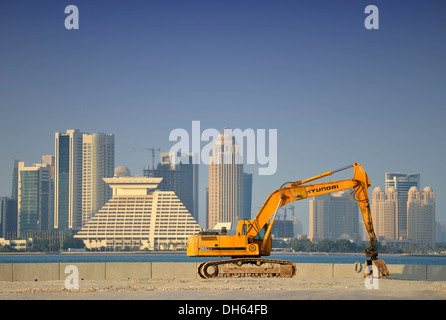 Boom edilizio a Doha, escavatore Hyundai di fronte allo skyline di Doha con Doha Sheraton Hotel Four Seasons Hotel Foto Stock