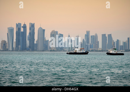 Rimorchiatori di fronte lo skyline di Doha al crepuscolo, Doha Corniche, Doha, Doha, Qatar Foto Stock