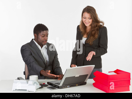 Giovane donna e un giovane uomo in ufficio con un computer portatile, avente una discussione Foto Stock