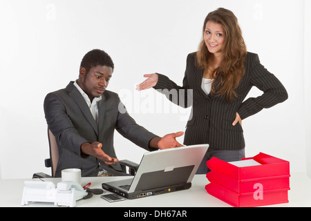 Giovane donna e un giovane uomo in ufficio con un computer portatile, avente una discussione Foto Stock