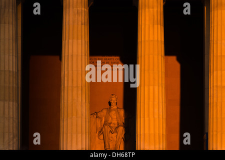 WASHINGTON DC, Stati Uniti: La statua del Lincoln Memorial, alta circa 3 metri, cattura la luce diretta del sole durante un'alba equinozio. Il preciso allineamento est-ovest del monumento consente alla luce del sole di illuminare la figura seduta di Daniel Chester French solo vicino agli equinozi primaverili e autunnali. Il sole nascente crea drammatici effetti di luce all'interno della camera commemorativa. Foto Stock