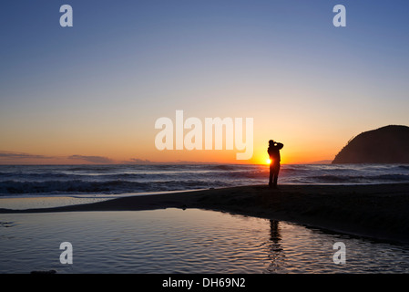 Un fotografo è in piedi sulla spiaggia di Levanto al tramonto, cinque terre Liguria, Italia, Europa, publicground Foto Stock