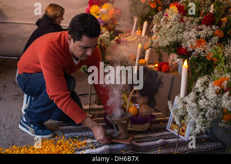 New York, NY, 31 ottobre 2013. Juan Carlos Aguirre, Direttore Esecutivo della mano a mano, aggiunge copal un censore davanti al pubblico altare. Nel giorno della commemorazione di tutti i defunti, El Dia de los Muertos, o il giorno dei morti e le offerte sono posti su un altare in ricordo del defunto la famiglia e gli amici. Credit: Ed Lefkowicz/Alamy Live News Foto Stock