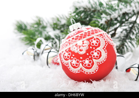 Red palla di Natale e rami di abete con decorazioni sulla neve Foto Stock
