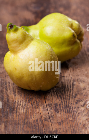 Due mele cotogne su un asse di legno Foto Stock