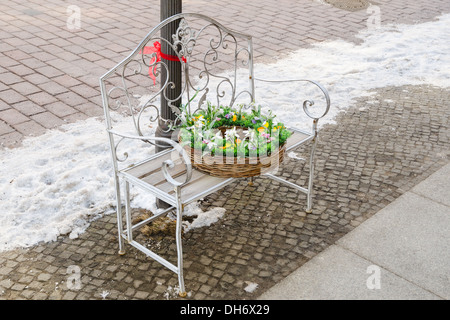 Cesto in Vimini con fiori di primavera sul ferro battuto panchina Foto Stock