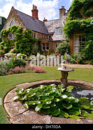 Rotondo piccolo giardino ornamentale laghetto e fontana situato in un giardino di Coton Manor House, Coton, Northamptonshire, Regno Unito. Foto Stock