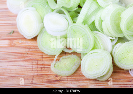 I porri tagliati ad anelli sul tagliere di legno. Foto Stock