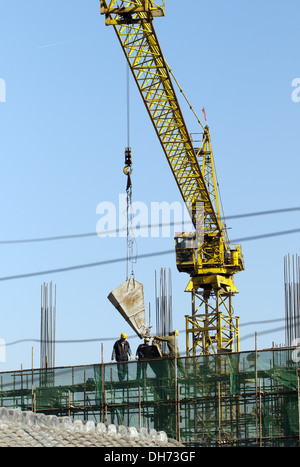 Costruttori che utilizzano una gru per caricare il cemento in un cantiere a Pechino, mentre lavorano alla costruzione di un nuovo edificio sostenuto da ponteggi. © Olli Geibel Foto Stock