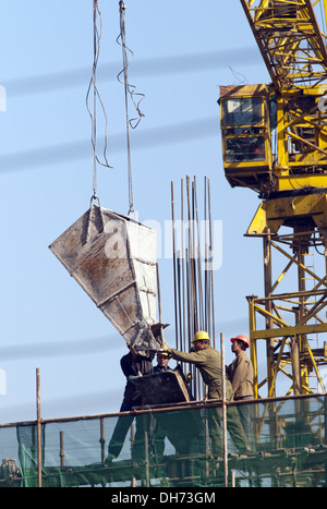 Costruttori che utilizzano una gru per caricare il cemento in un cantiere a Pechino, mentre lavorano alla costruzione di un nuovo edificio sostenuto da ponteggi. © Olli Geibel Foto Stock