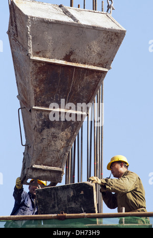 Costruttori che utilizzano una gru per caricare il cemento in un cantiere a Pechino, mentre lavorano alla costruzione di un nuovo edificio sostenuto da ponteggi. © Olli Geibel Foto Stock