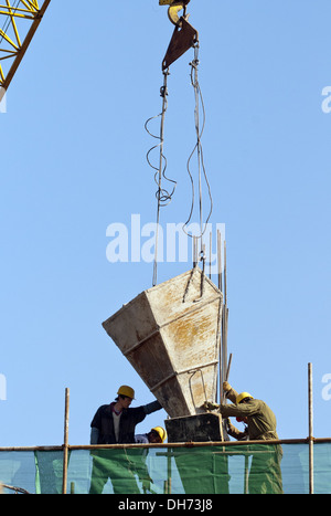 Costruttori che utilizzano una gru per caricare il cemento in un cantiere a Pechino, mentre lavorano alla costruzione di un nuovo edificio sostenuto da ponteggi. © Olli Geibel Foto Stock