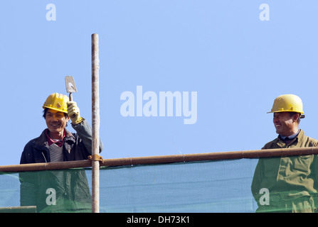 Costruttori che utilizzano una gru per caricare il cemento in un cantiere a Pechino, mentre lavorano alla costruzione di un nuovo edificio sostenuto da ponteggi. © Olli Geibel Foto Stock