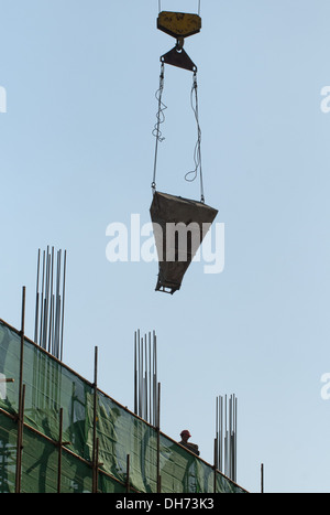 Costruttori che utilizzano una gru per caricare il cemento in un cantiere a Pechino, mentre lavorano alla costruzione di un nuovo edificio sostenuto da ponteggi. © Olli Geibel Foto Stock