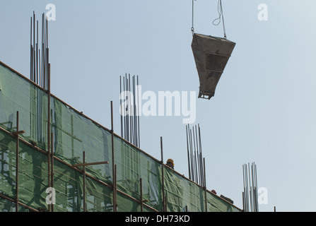 Costruttori che utilizzano una gru per caricare il cemento in un cantiere a Pechino, mentre lavorano alla costruzione di un nuovo edificio sostenuto da ponteggi. © Olli Geibel Foto Stock