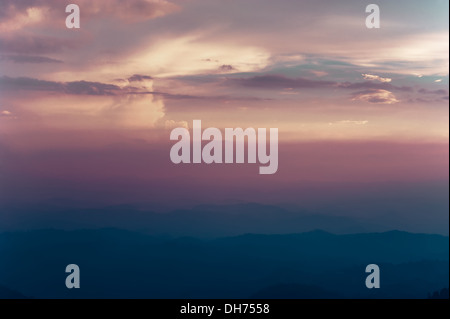 Bellissimo Cielo di tramonto colori con drammatica nuvole e Misty Mountains silhouette. India del sud paesaggio. Munnar Kerala, India Foto Stock