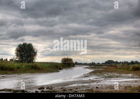 Cove lungo il fiume olandese Lek sotto le nuvole scure, Nieuw-Lekkerland, South Holland, Paesi Bassi Foto Stock