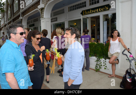 Un gruppo misto di persone bere Bloody Mary's mentre aspetta con altri di essere seduti al di fuori di Babette's restaurant East Hampton Foto Stock