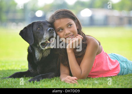 Ragazza con cane posa sull'erba Foto Stock