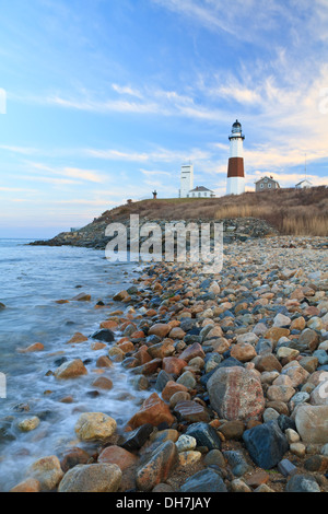 Delle onde dell'Oceano Atlantico con la schiuma sulle rocce sotto il faro di Montauk all'estremità orientale di Long Island, New York Foto Stock